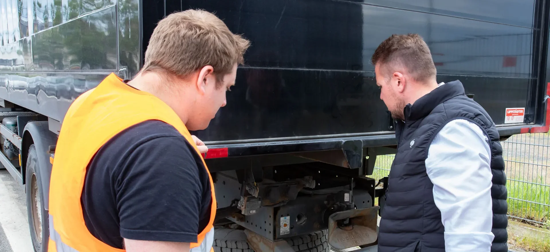 Zwei Männer kucken auf eine LKW-Kupplung