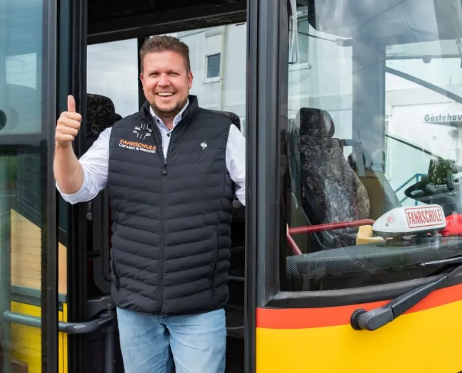 Fahrlehrer Manuel Preikschat zeigt Daumen hoch aus dem Bus