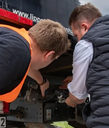 zwei Männer schrauben an einem LKW