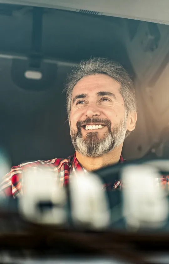 Älterer Mann, anscheinend ein LKW-Fahrer von vorne durch die Windschutzscheibe fotografiert