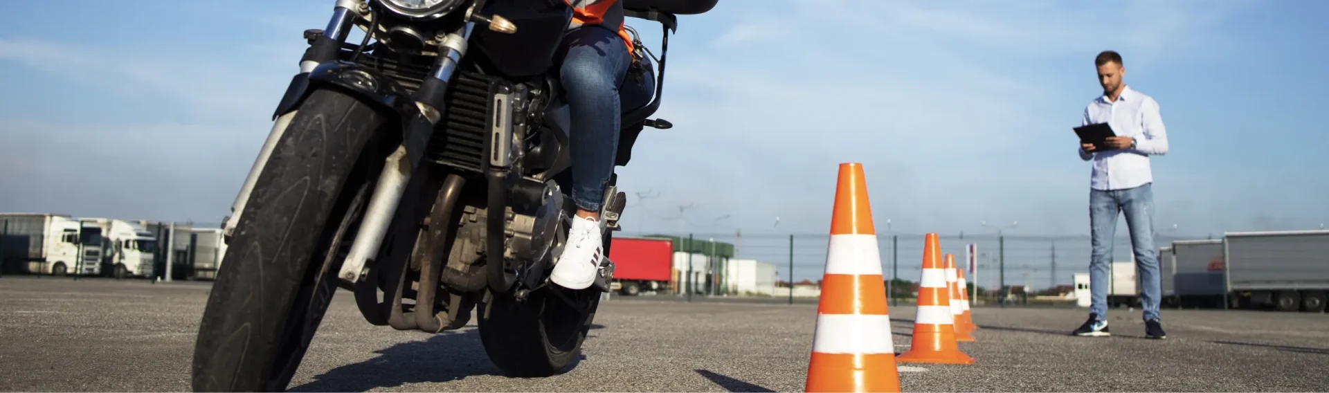 Prüfer beobachtet Motorad-Fahrschüler bei der Fahrt durch Pylone