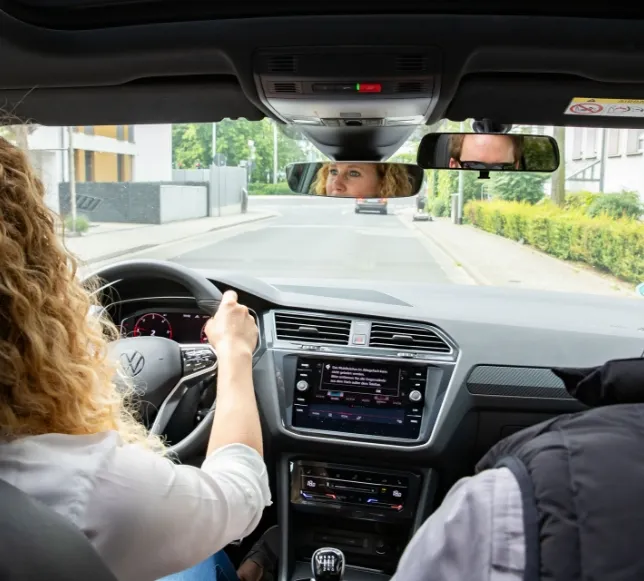 Fahrlehrer und eine Fahrschülerin sitzen gemeinsam in einem Auto und führen eine Fahrstunde durch